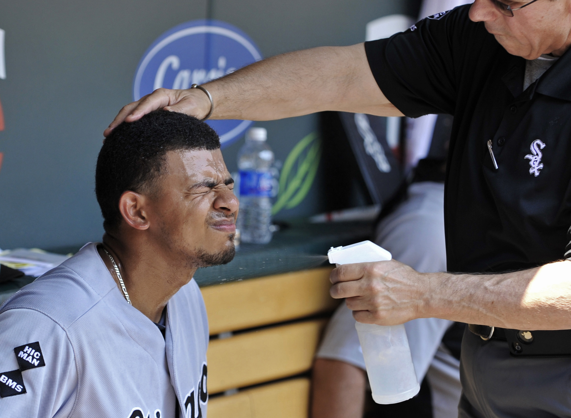 Chicago White Sox' Eduardo Escobar closes his eyes as trainer Herm Schneider sprays him with cool water during a baseball game against the Minnesota Twins in Minneapolis on Wednesday.