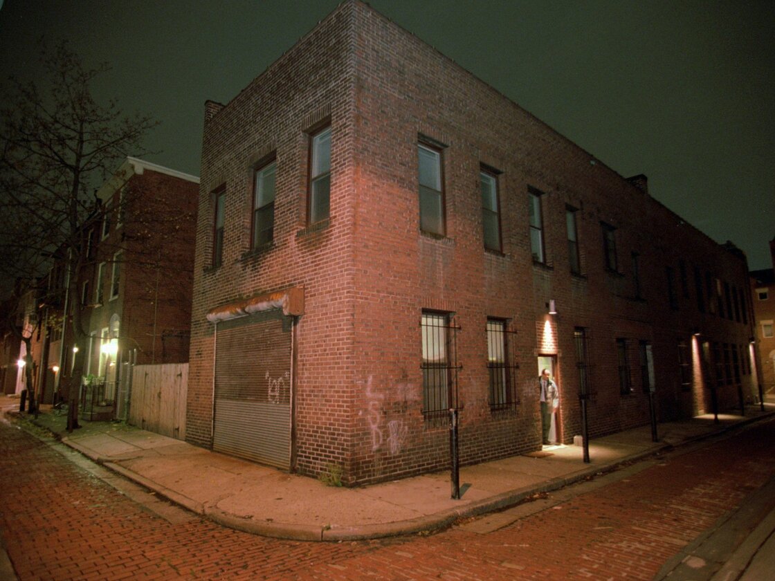 A detective peers from the doorway of a Center City Philadelphia apartment building.