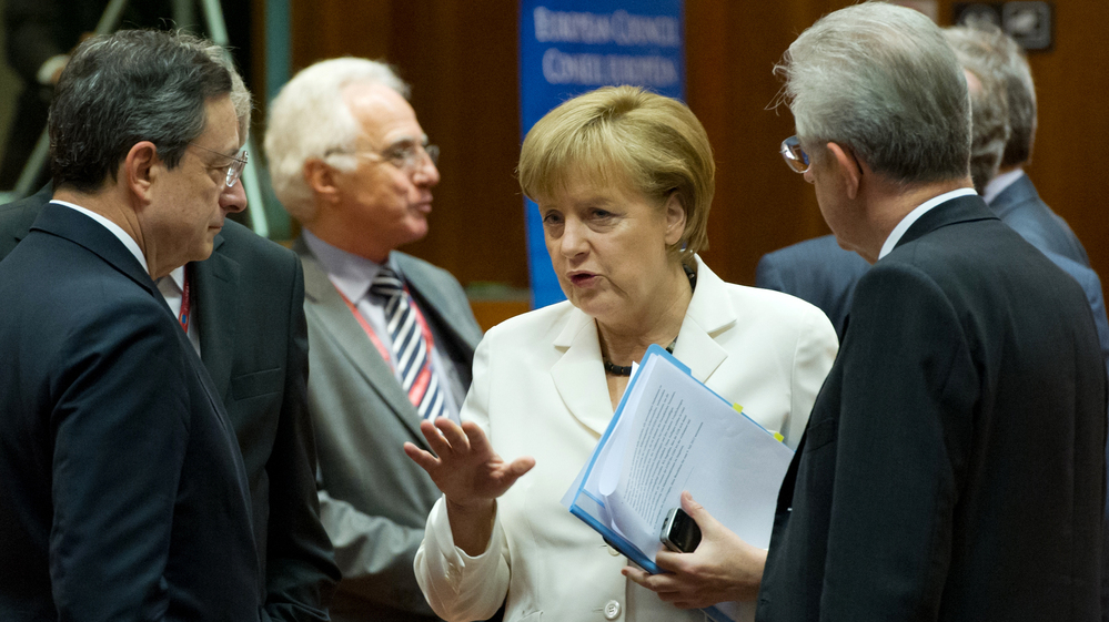 German Chancellor Angela Merkel talks with European Central Bank President Mario Draghi (left) and Italian Prime Minister Mario Monti (right) during the summit of European leaders in Brussels.