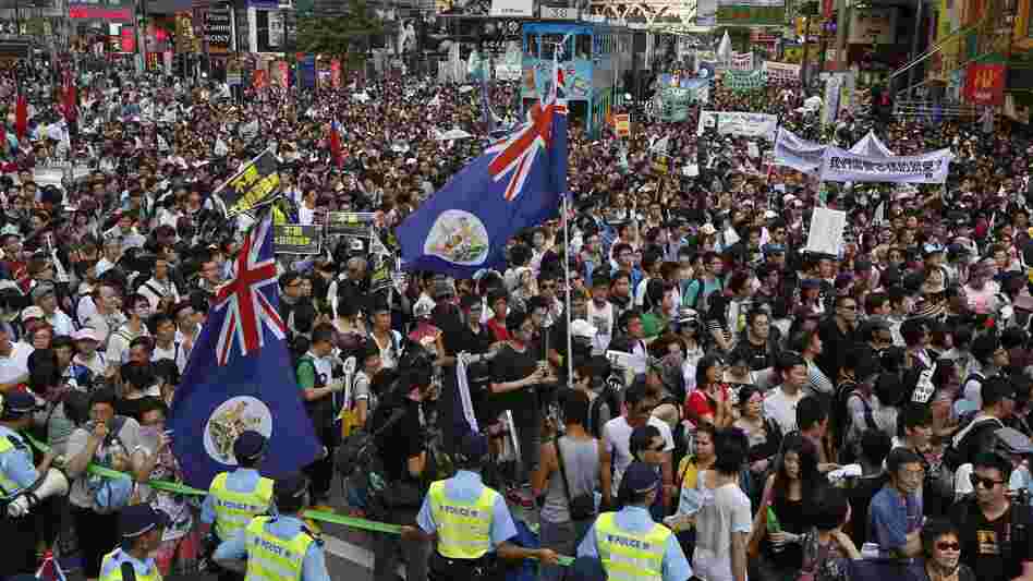 Flags from Hong Kong's colonial period fly over crowds in Victoria park on Sunday.Huge crowds pack Hong Kong's Victoria park, marching through the city's streets Sunday to express their dissatisfaction with the new leader.
