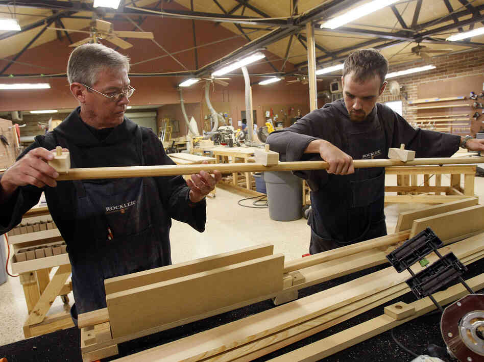 Benedictine Brother Brian Harrington (left) and novice Dustin Bernard pull a casket handle from a press in a workshop at St. Joseph Abbey in Covington, La.