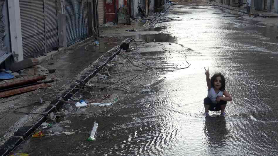 A handout image released by the Syrian opposition's Shaam News Network on Monday shows a girl flashing the sign for victory in a destroyed street flooded with water in the restive central city of Homs. A handout image released by the Syrian opposition's Shaam News Network on Monday shows a girl flashing the sign for victory in a destroyed street flooded with water in the restive central city of Homs.