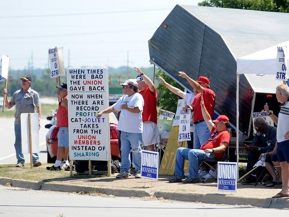 Striking workers picket outside a Caterpillar plant in Joliet, Ill. The work stoppage is now entering its third month.