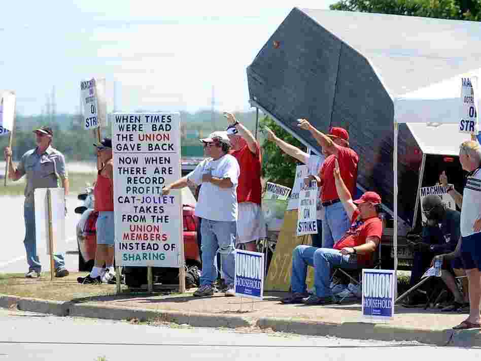 Striking workers picket outside a Caterpillar plant in Joliet, Ill. The work stoppage is now entering its third month.