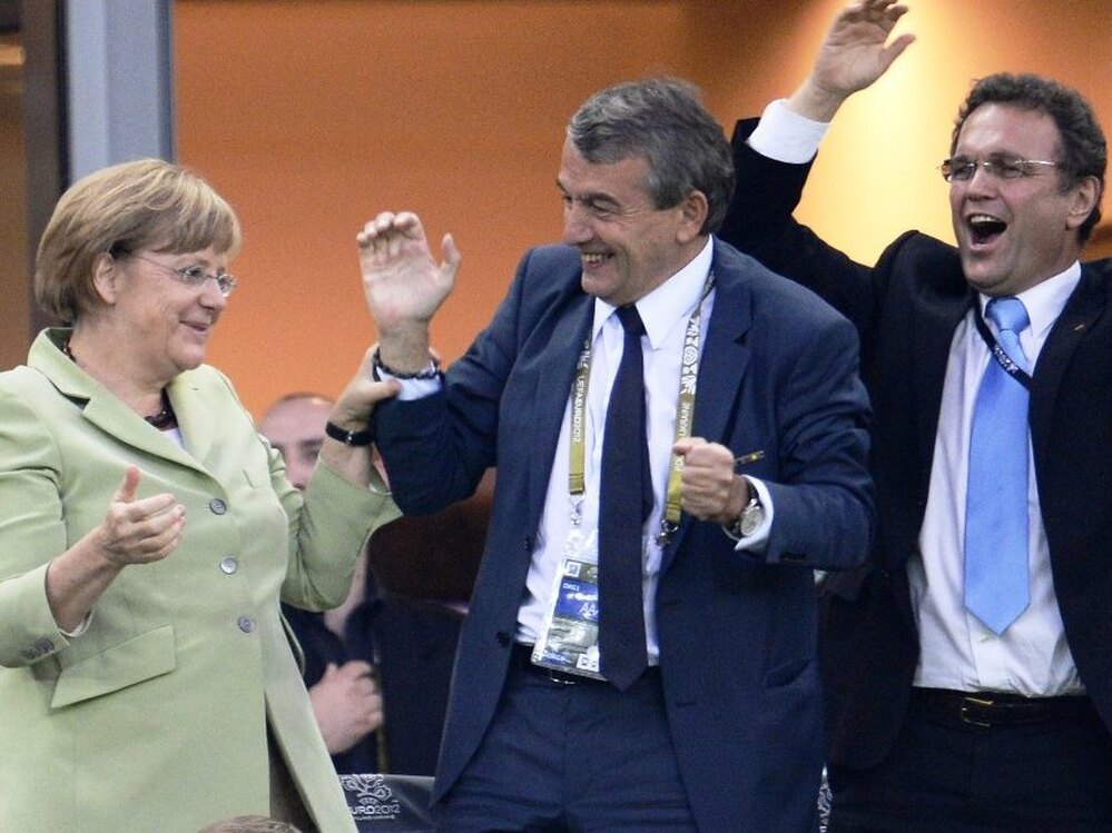German Chancellor Angela Merkel, German football association president Wolfgang Niersbach and German Interior Minister Hans-Peter Friedrich celebrate after Philip Lahm scored against Greece during the Euro 2012