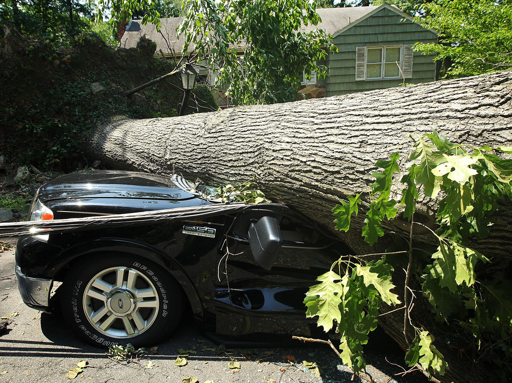 A fallen tree crushes a truck in Falls Church, Va., outside Washington. Storms across the Midwest and East downed trees and power lines and left millions without power.
