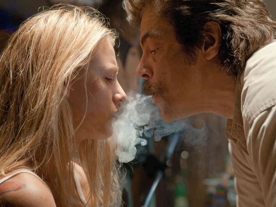 O (Blake Lively), Ben's and Chon's girlfriend, has a not-so-friendly chat with Lado (Benicio Del Toro), an enforcer for the Tijuana cartel that kidnaps O to ensure a drug deal goes through.