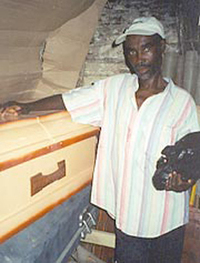 St. Ker, in 2001, with the coffin he picked out for himself and a plastic bag that contains his funeral clothes. With the help of medicine, he has fought off AIDS and sold the coffin.