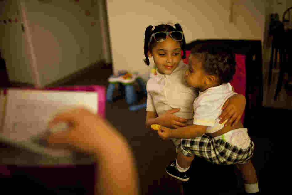 Shyanne (left) holds 1-year-old Makai, as Stepp checks to see if all of Shyanne's homework has been completed.