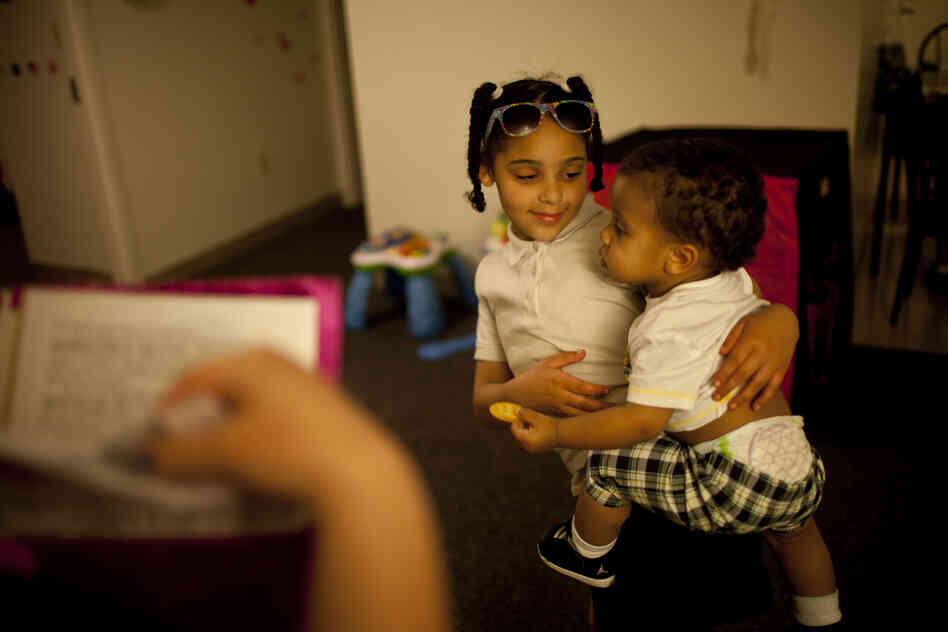 Shyanne (left) holds 1-year-old Makai, as Stepp checks to see if all of Shyanne's homework has been completed.