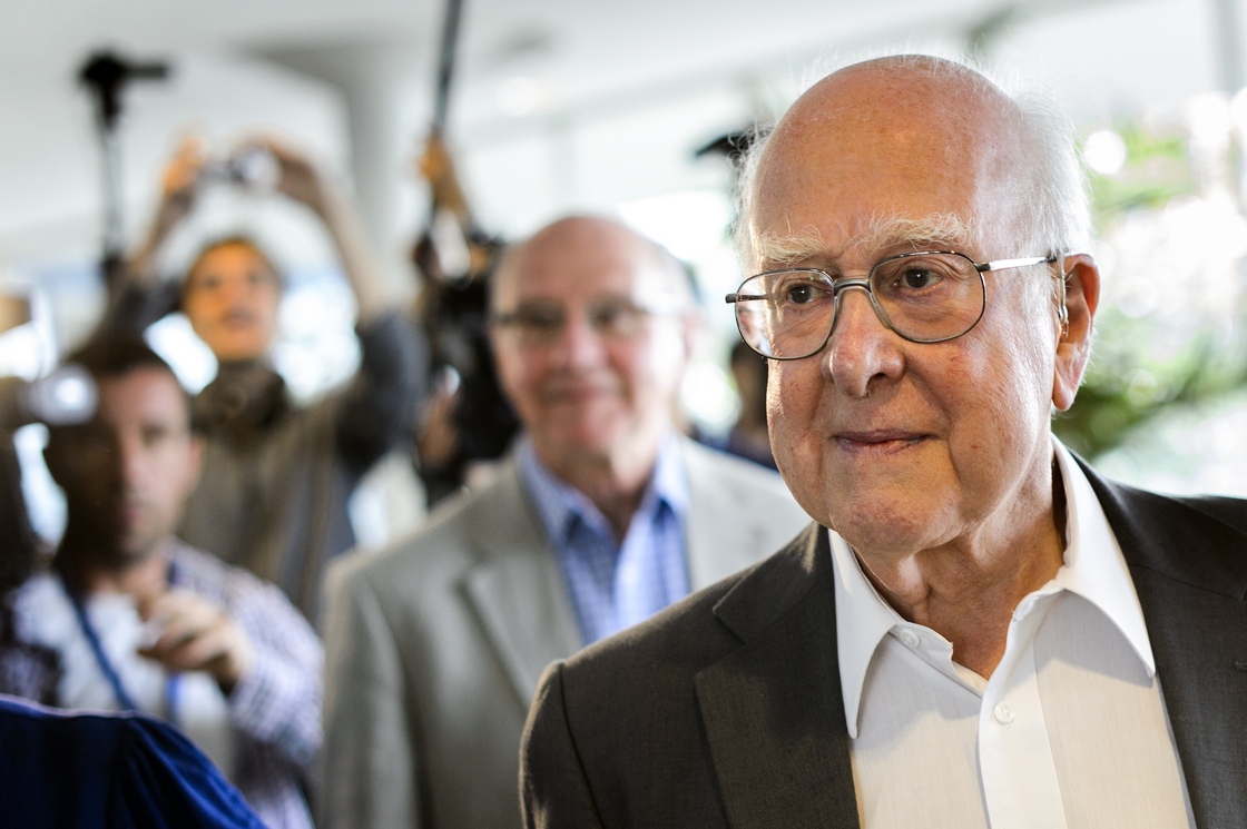British physicist Peter Higgs, right, arrives for the opening of a seminar to deliver the latest update in the 50-year bid to explain a riddle of fundamental matter in the search for a particle called the Higgs boson.