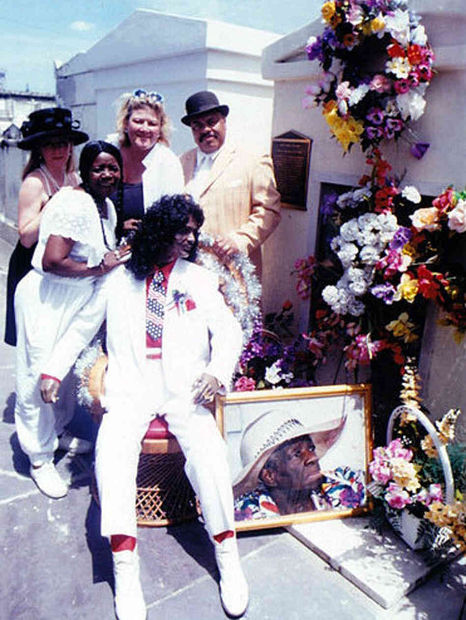 Antoinette K-Doe (second from the left) stands with friends around a statue of her deceased husband, Ernie, at the St. Louis No. 2 tomb. Antoinette is buried in the tomb, and her mother — Ernie K-Doe's second and favorite mother-in-law, Leola Clark — is shown in the portrait. Clark is buried in the tomb, too.