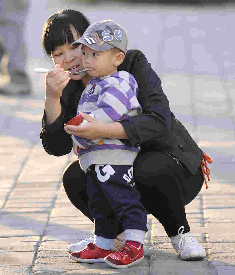 A mother feeds her child in Beijing, Oct. 24, 2011. Experts say many Chinese do not want to have additional children, regardless of official policy. A mother feeds her child in Beijing, Oct. 24, 2011. Experts say many Chinese do not want to have additional children, regardless of official policy.