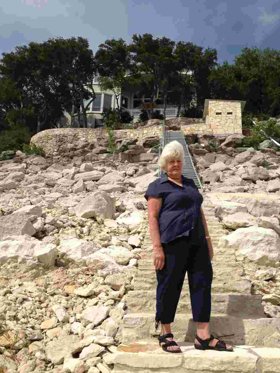 Connie Ripley stands 30 feet below the normal water line in front of her house on Lake Travis, which is half full because of the ongoing drought.