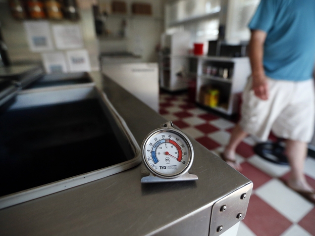 A thermometer reads the temperature atop an empty Maryland ice cream store freezer on Tuesday.  Many grocery stores and restaurants are still waiting for power to return for the first time since last weekend's severe storms.