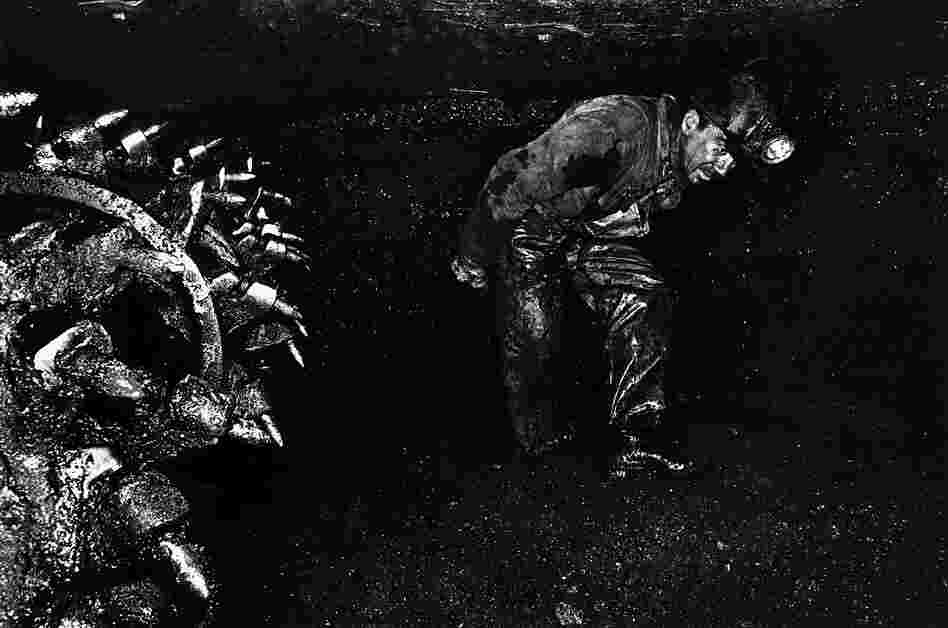 A coal miner in a classic posture walks by the bits of a continuous mining machine in Clearfield County, Pa., in 1976.