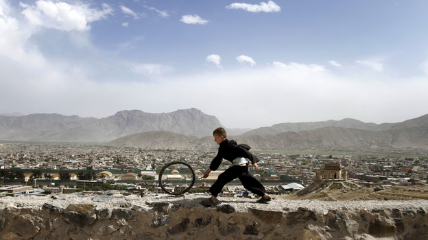 An Afghan boy pushes a wheel on the Naderkhan hill in Kabul, Afghanistan, in May. As more people have crowded to Kabul, the city center has become like a buoy floating in a sea of sprawl.