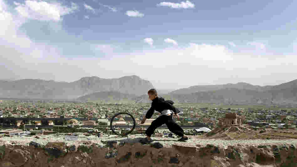 An Afghan boy pushes a wheel on the Naderkhan hill in Kabul, Afghanistan, in May. As more people have crowded to Kabul, the city center has become like a buoy floating in a sea of sprawl.