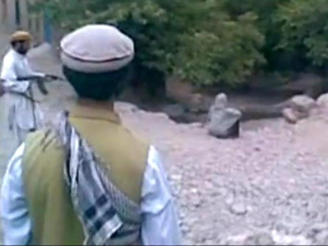 A screen grab from the video of a public execution reportedly carried out last month in Afghanistan. The victim is sitting with her back to the executioner, who is at left.