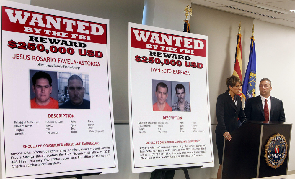 With wanted posters off to the side, James L. Turgal, Jr., right, FBI Special Agent in Charge, listens as Laura E. Duffy, United States Attorney Southern District of California, announces the indictments on five suspects involved in the death of U.S. Border Patrol agent Brian Terry on Monday.