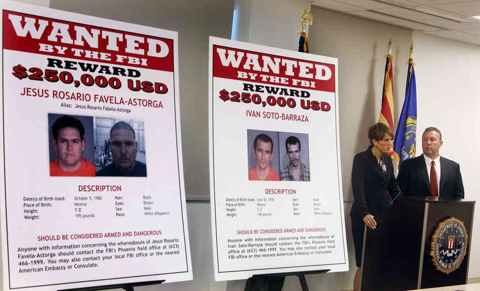 With wanted posters off to the side, James L. Turgal, Jr., right, FBI Special Agent in Charge, listens as Laura E. Duffy, United States Attorney Southern District of California, announces the indictments on five suspects involved in the death of U.S. Border Patrol agent Brian Terry on Monday.