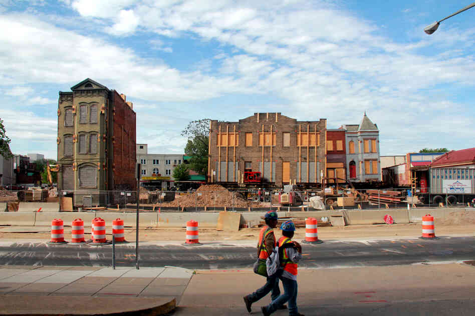 Construction workers walk by the site of a major building-moving project behind NPR headquarters in Washington, D.C.