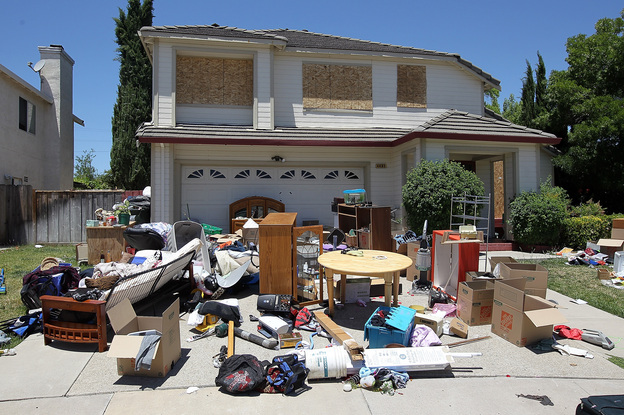 Furniture and personal belongings sit in front of a house that appears to have been foreclosed on in Antioch, California.