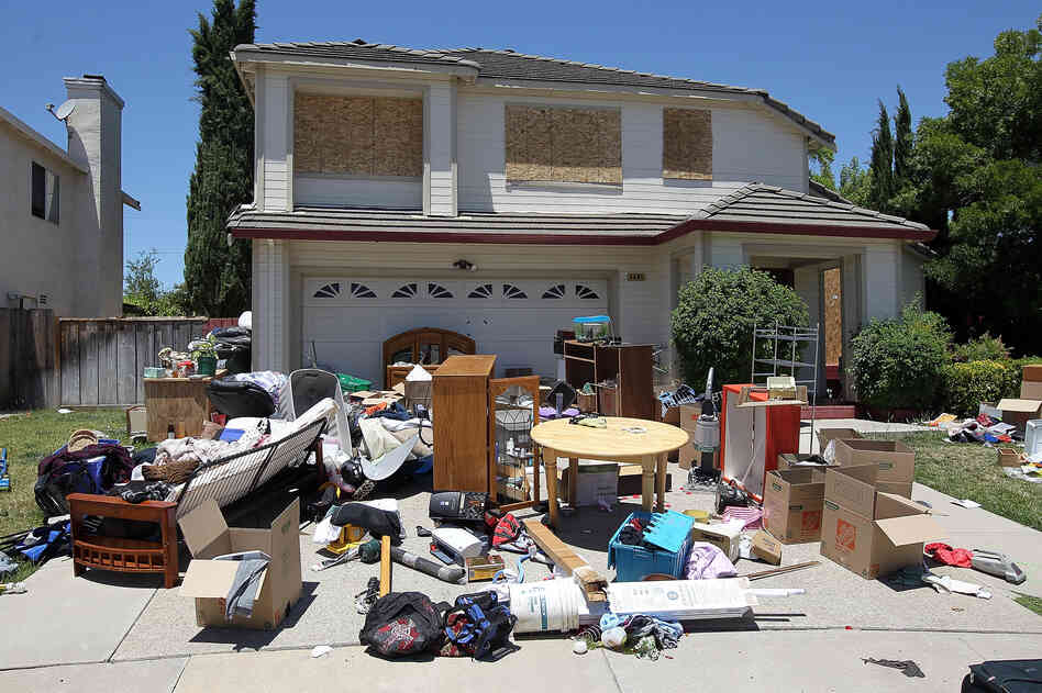 Furniture and personal belongings sit in front of a house that appears to have been foreclosed on in Antioch, California.