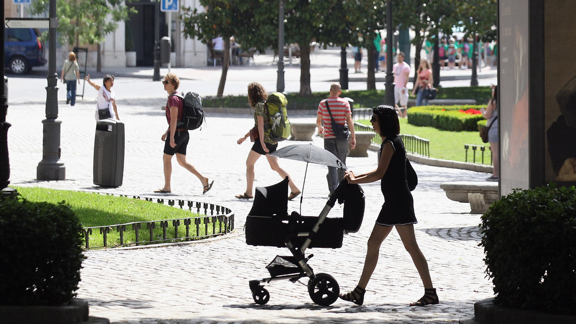 A woman pushes a pram though the Plaza de Murillo on July 3 in Madrid. Spain's custom for multiple families to live under the same roof has tied them closer together as well as their wallets. The country has the highest unemployment rate in the Eurozone, and government benefits help aid those out of work.
