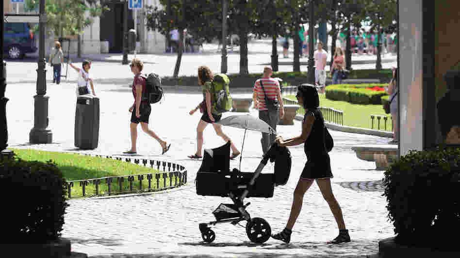 A woman pushes a pram though the Plaza de Murillo on July 3 in Madrid. Spain's custom for multiple families to live under the same roof has tied them closer together as well as their wallets. The country has the highest unemployment rate in the Eurozone, and government benefits help aid those out of work.