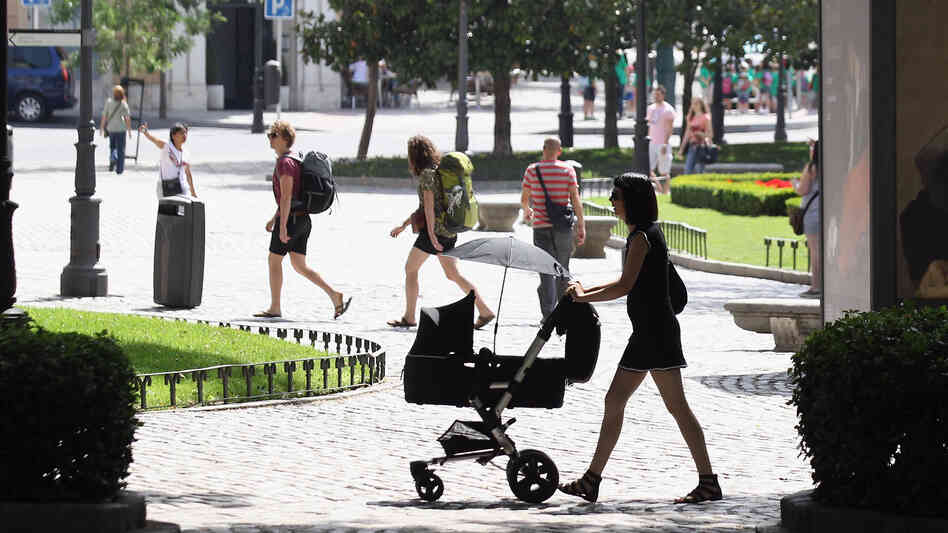 A woman pushes a pram though the Plaza de Murillo on July 3 in Madrid. Spain's custom for multiple families to live under the same roof has tied them closer together as well as their wallets. The country has the highest unemployment rate in the Eurozone, and government benefits help aid those out of work.