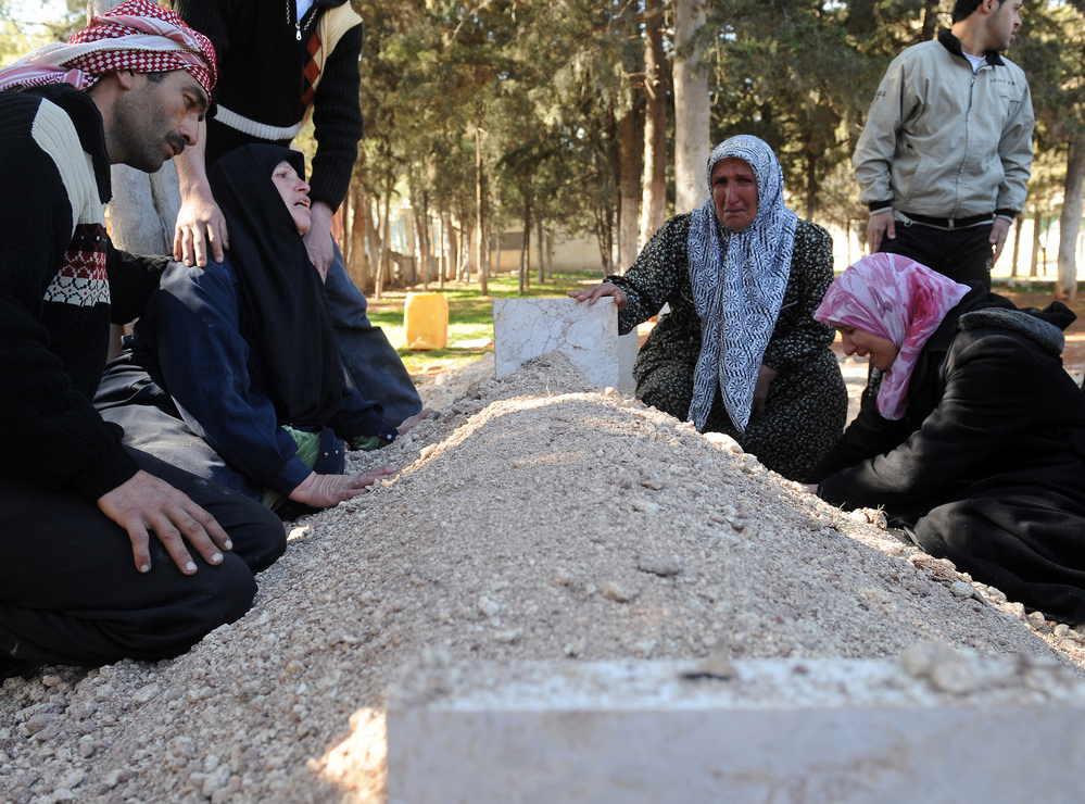 In February, these Syrians mourned over the fresh grave of a relative following a funeral for victims killed in violence in Idlib.