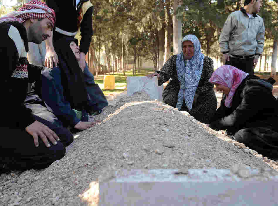 In February, these Syrians mourned over the fresh grave of a relative following a funeral for victims killed in violence in Idlib.