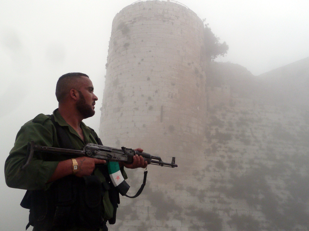 A member of the Free Syrian Army stands near a medieval castle outside Homs, a flashpoint for much of the recent fighting, last month. The Syrian army continues to wage offensives against the rebels in many places, but the rebels say they can move back and forth between northwest Syria and southern Turkey.