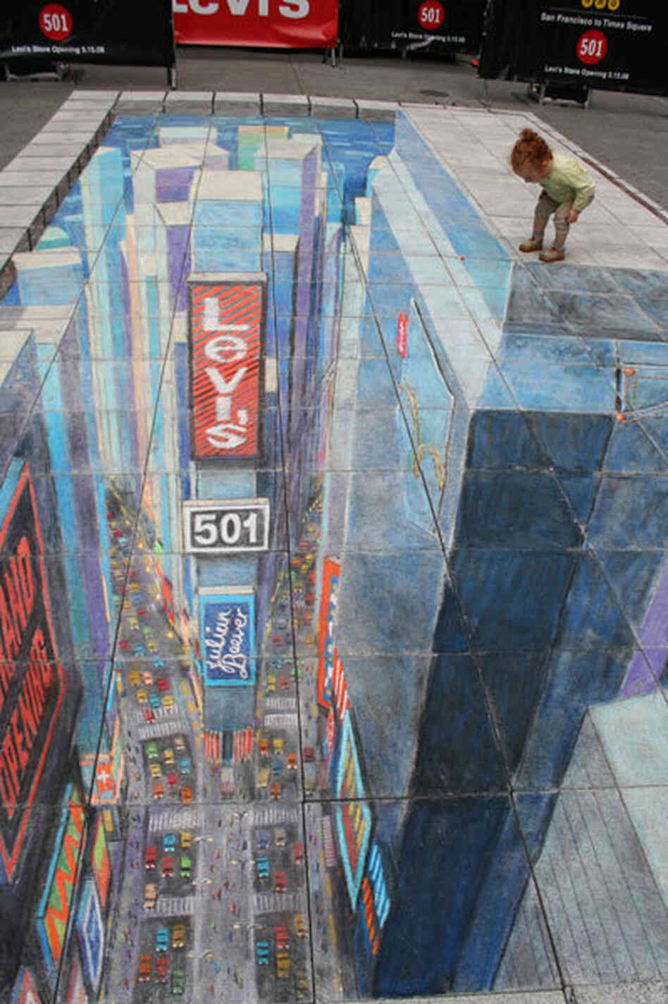 A toddler peers over the edge of a chalk drawing of a building.