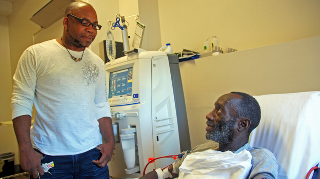 While Kenya Jackson (right) is on his thrice-weekly dialysis treatment, community health worker Greg Jules talks to him about taking his medication.