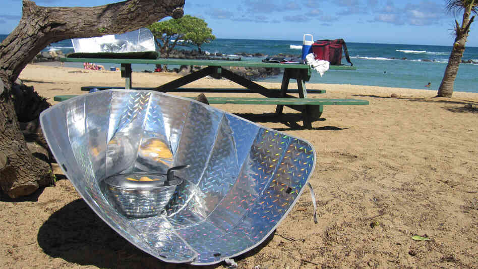 Corn dogs sizzle in a solar cooker made from reflective car windshield shades.