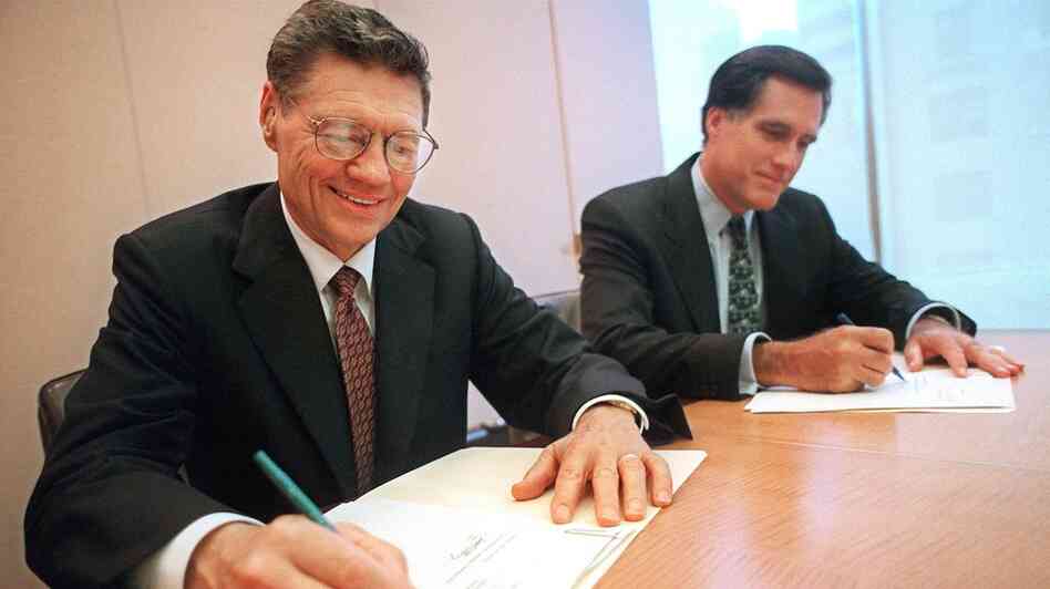 Thomas Monaghan (left), founder and chairman of Domino's Pizza, signs an agreement to sell a "significant portion" of his stake in the company to Mitt Romney's Bain Capital, in 1998. Romney, then Bain's CEO, maintains that he left the firm the following year.