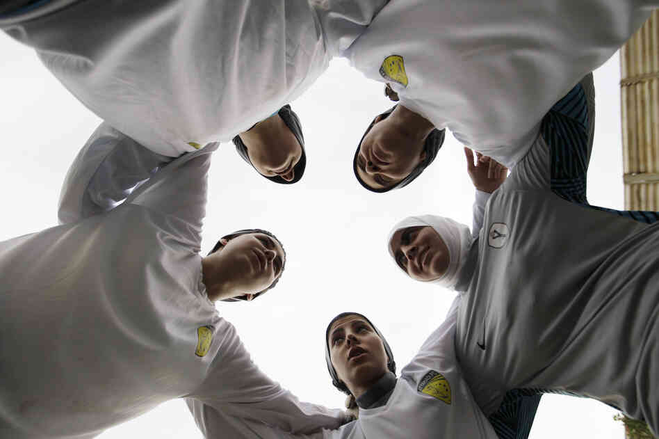 In this May photo, members of a Saudi female soccer team listen to their captain, Rawh Abdullah, before their training session at a secret location in Riyadh. The decision to send female athletes to the Olympics will definitely have consequences at home.