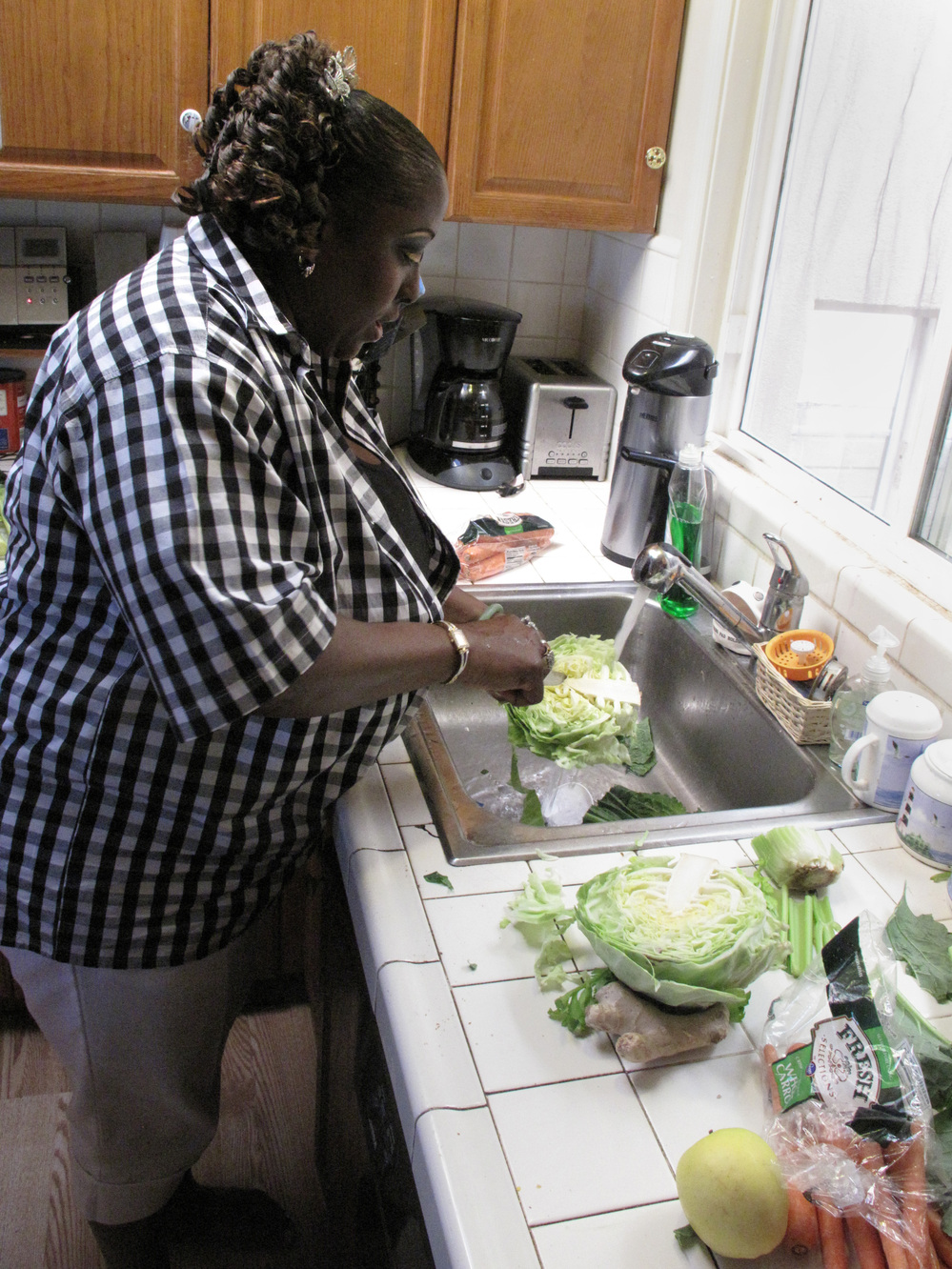 Yovanda Dixon washes vegetables in her San Francisco home to prepare a demonstration for her support group.