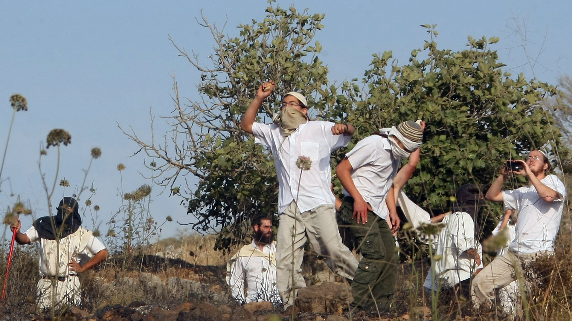 Jewish settlers in the West Bank throw stones during clashes with Palestinians near the city of Nablus on May 19. A new report says violence by settlers directed at West Bank Palestinians is up sharply over the past three years. (Image credit: AFP/Getty Images)