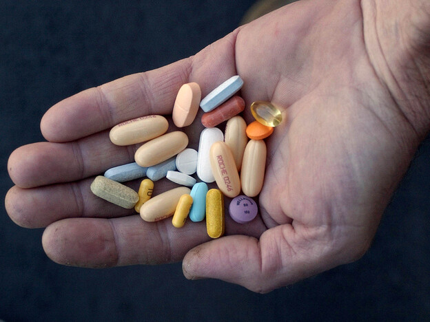 HIV treatment regimens, like the pills in this patient's hand, keep AIDS at bay, but can take a harsh physical toll over the course of many years.