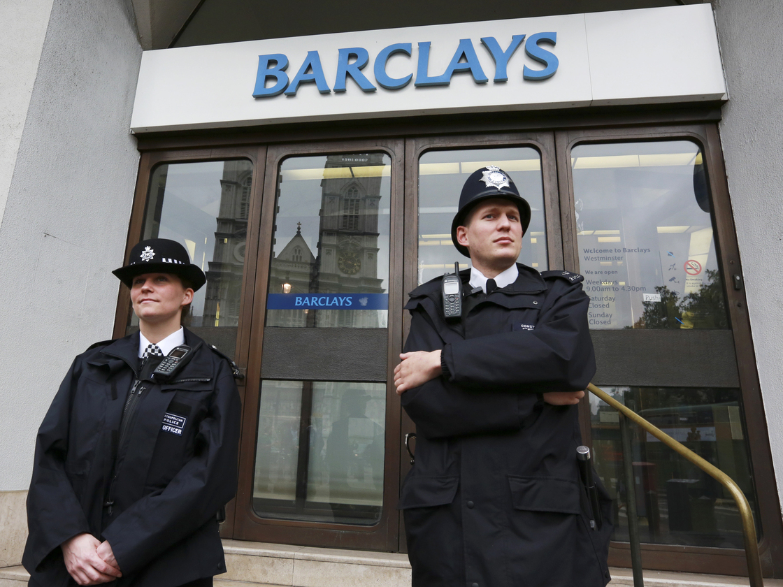 Police wait for protesters to appear at a branch of Barclays Bank in London on July 4.