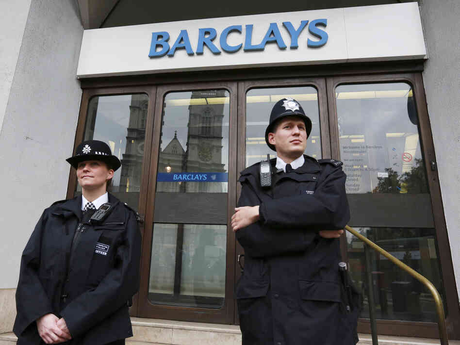 Police wait for protesters to appear at a branch of Barclays Bank in London on July 4.