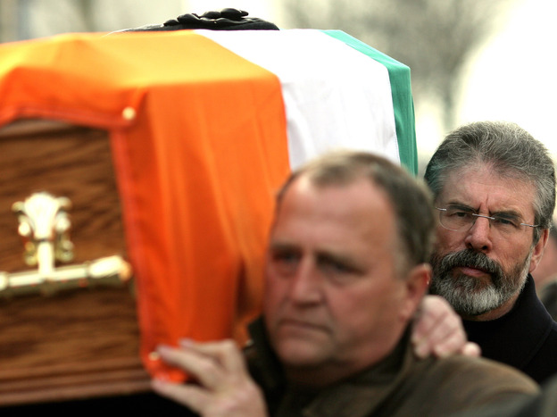 Sinn Fein President Gerry Adams, right, carries the coffin of senior IRA commander Brendan Hughes, in West Belfast, Northern Ireland.