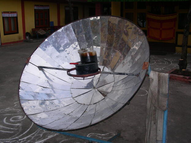 A parabolic solar cooker heats up a tea kettle in Nepal.