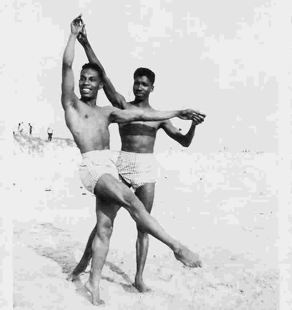 Two men dance on the beach.