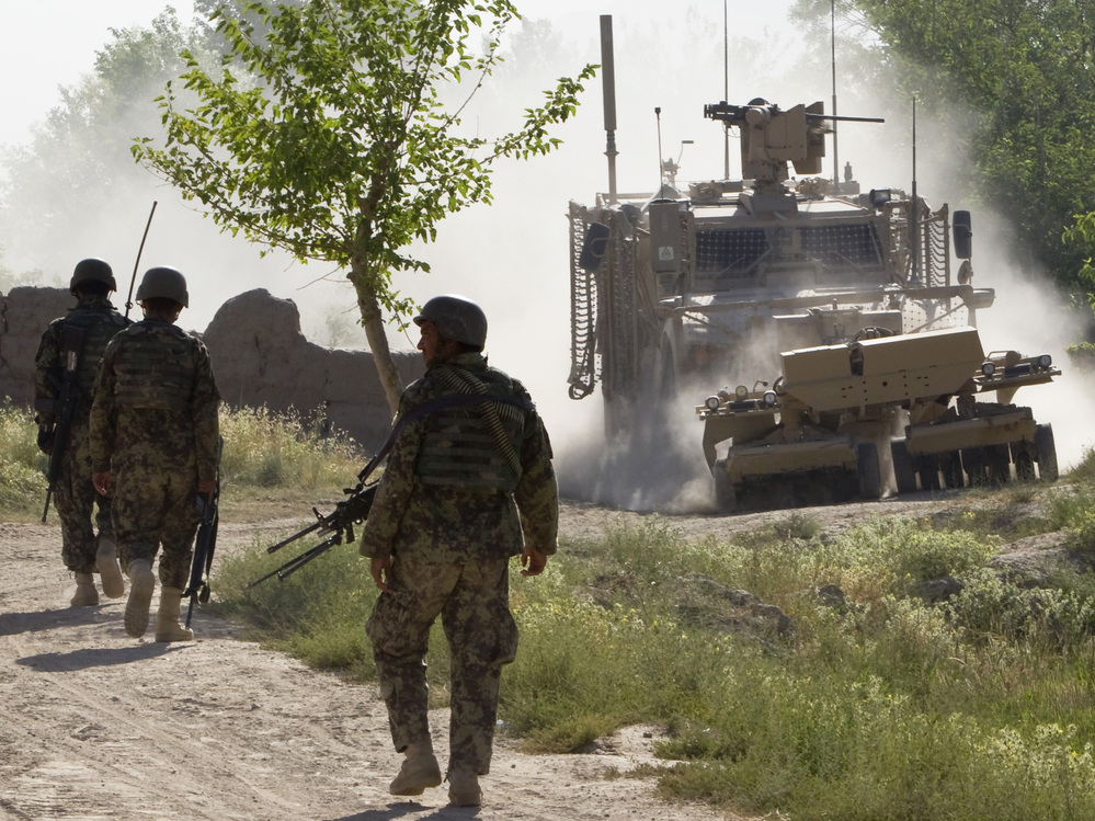 Afghan soldiers walk toward a U.S. Army mine-sweeping vehicle in southern Afghanistan on June 10. Roadside bombs remain a major threat to U.S. and Afghan troops, as well as civilians.