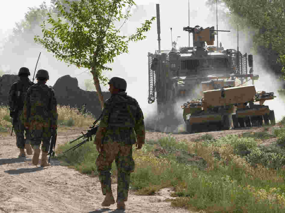 Afghan soldiers walk toward a U.S. Army mine-sweeping vehicle in southern Afghanistan on June 10. Roadside bombs remain a major threat to U.S. and Afghan troops, as well as civilians.
