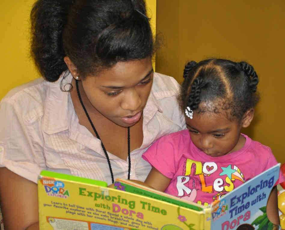A volunteer reads a book with a visitor at The Homeless Children's Playtime Project.